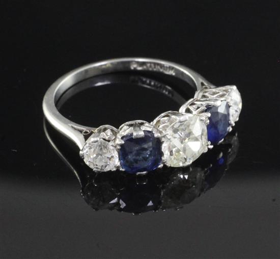 A mid 20th century platinum and graduated five stone sapphire and diamond half hoop ring, size M.
